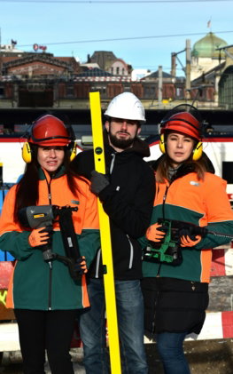 Three construction workers holding tools and level